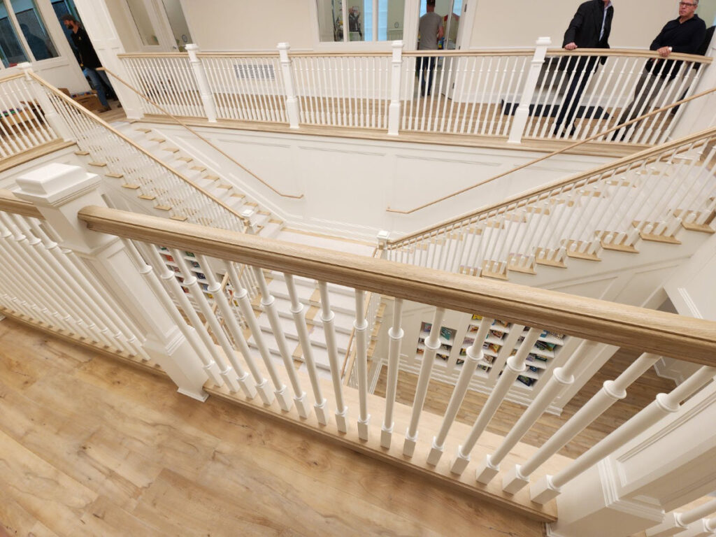 large stairwell with finished hardwood and painted railings